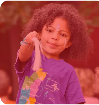 A child with face paint holding a ribbon streamer at a Y event.
