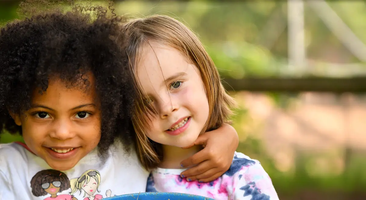 Two smiling children at a YMCA of Western North Carolina camp, holding a tray of things they found outdoors.
