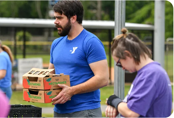 A YMCA volunteer carrying boxes of food for the community.