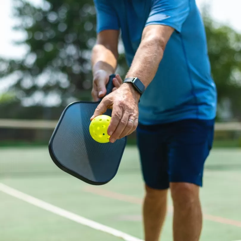Adult playing pickleball on an outside court.