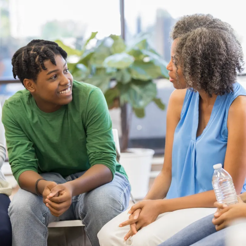 An adult woman talks to teenagers in a group.