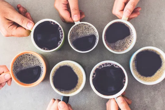A group of people's hands hold cups of coffee together.