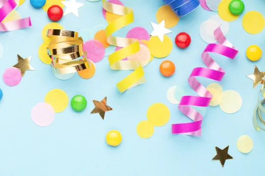 A background of birthday confetti and ribbons on a blue background.