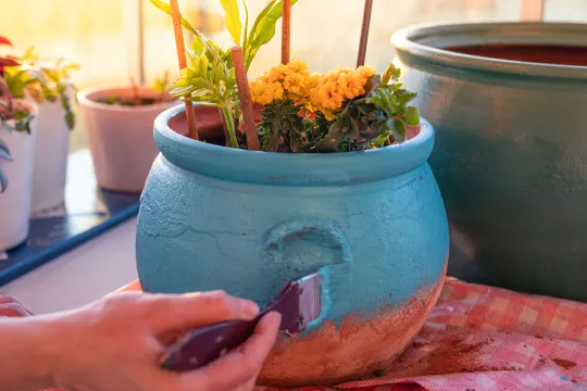 A pair of hands paint a flowerpot.