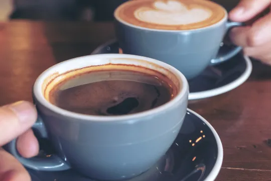 Two people hold cups of coffee.