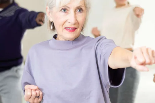 An older woman learns self defense in a group class.