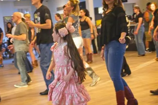 A family dances together in a group line dancing class.