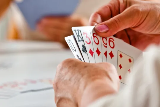A close-up of someone holding cards during a bridge game.
