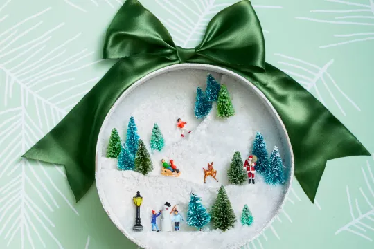 A winter diorama craft made with the lid of a mason jar.