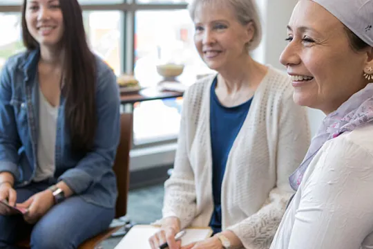 A group of diverse women sit together in a cancer support group for women.