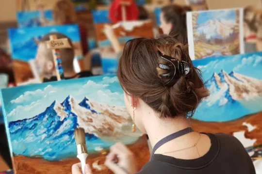 People participate in a Bob Ross painting class.