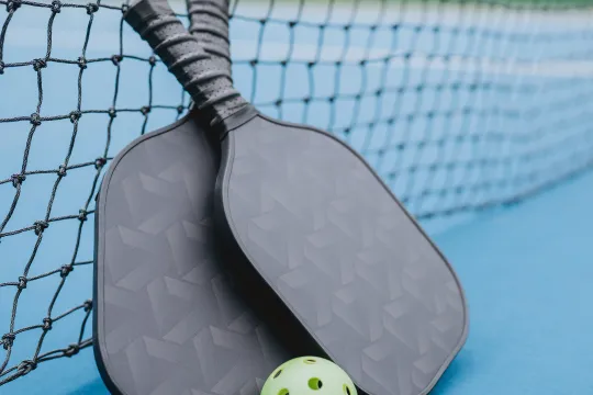 Two pickleball paddles on an outdoor court
