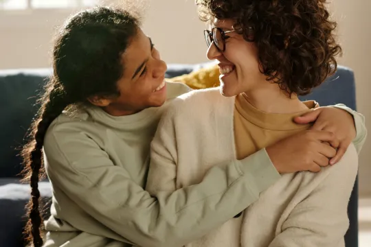 Mother smiling and embracing teenage daughter