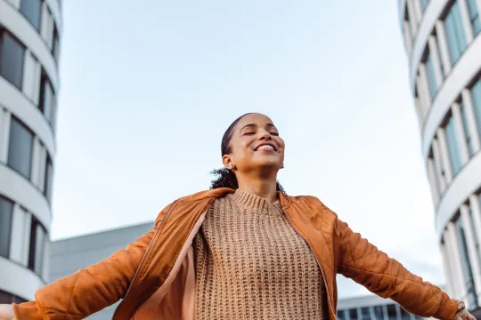 A woman stands outside and smiles with confidence.