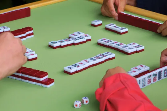 Close-up of three people's hands playing mahjong.