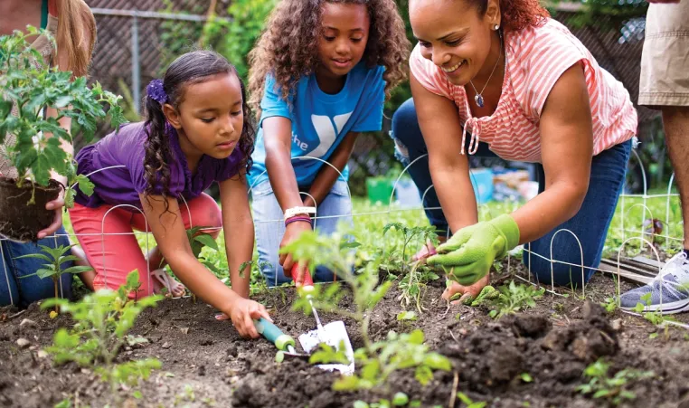Mother and her daughters volunteer in community garden.