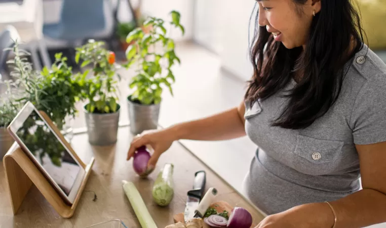 A woman follows a healthy recipe as she prepares vegetables in her kitchen.