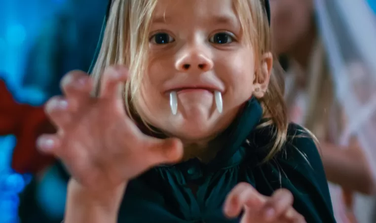 A little girl dressed as a vampire has fun at a Halloween party.