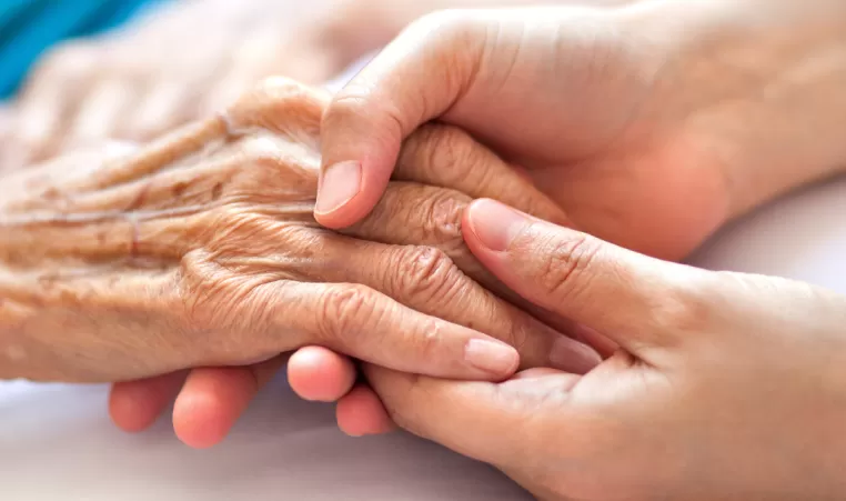 Two pairs of hands holding each other. One pair of hands is older than the other.