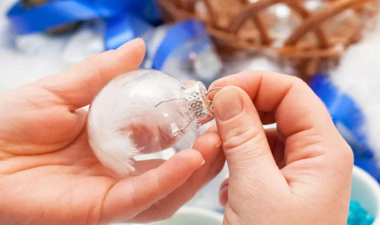 A closeup of a pair of hands making a Christmas ornament.