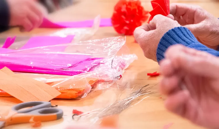 A pair of hands make paper crafts at a table.