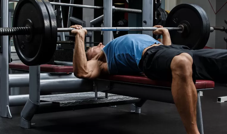 A man does a bench press using a barbell in the gym.
