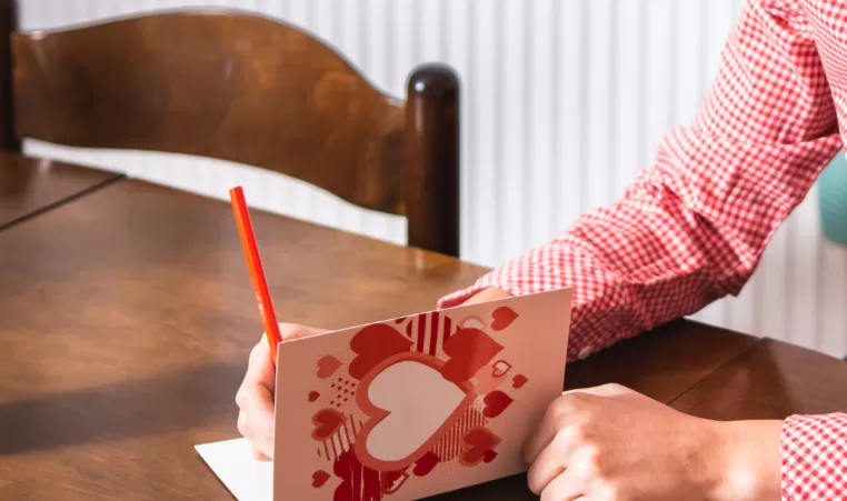 A woman signs a Valentine's Day card.