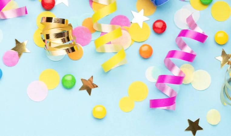 A background of birthday confetti and ribbons on a blue background.