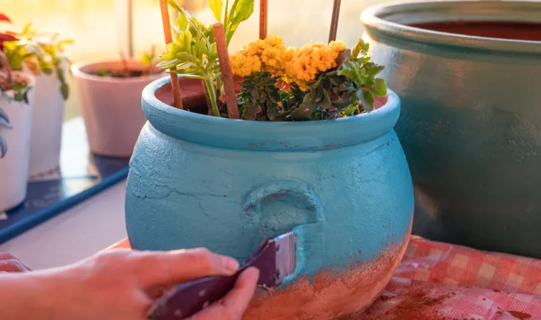 A pair of hands paint a flowerpot.