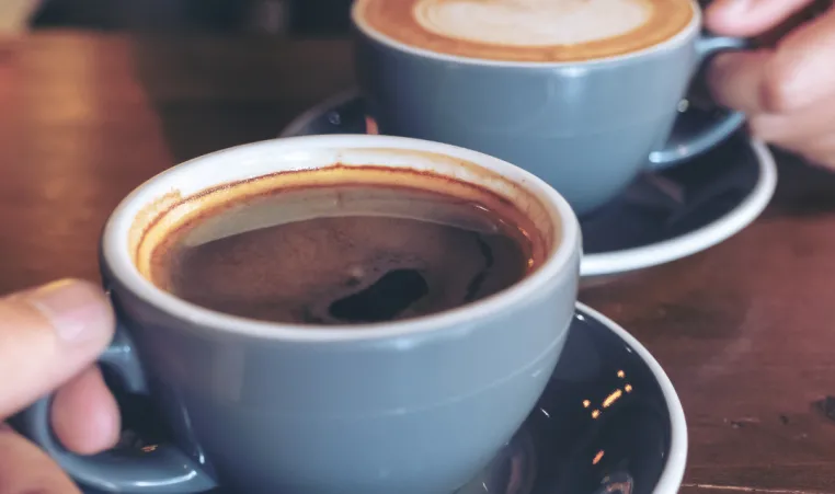 Two people hold cups of coffee.
