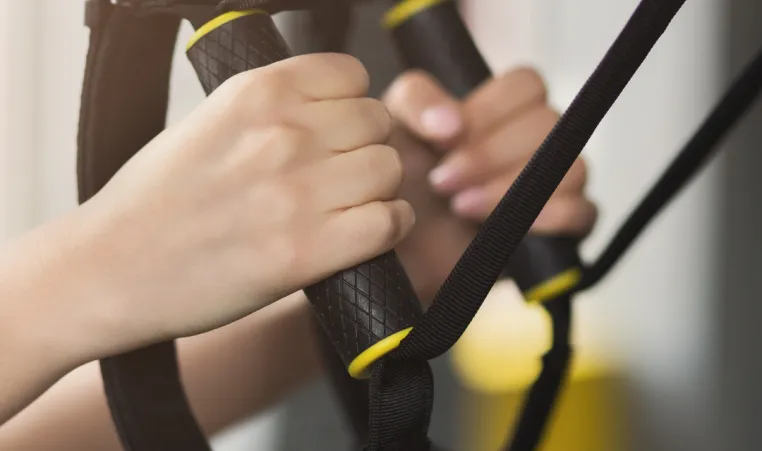 A close up of hands using TRX equipment during a group exercise class.