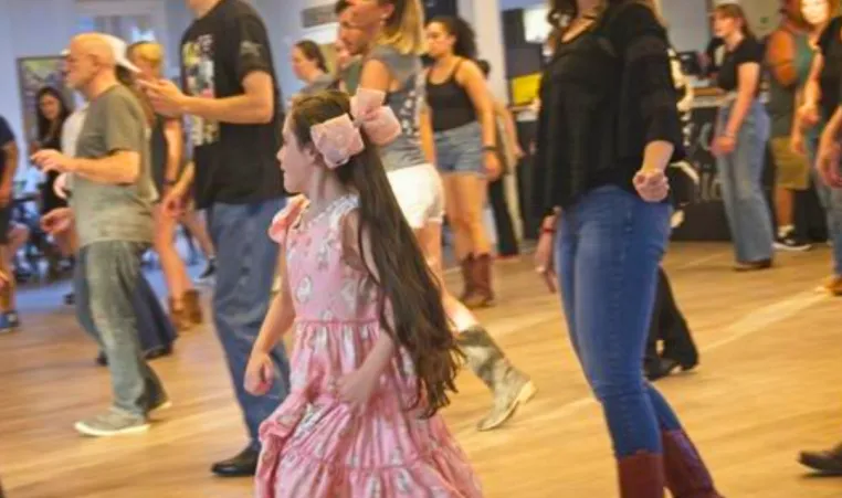 A family dances together in a group line dancing class.