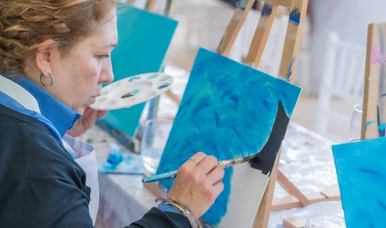 A group of people paint a winter scene during an art class.