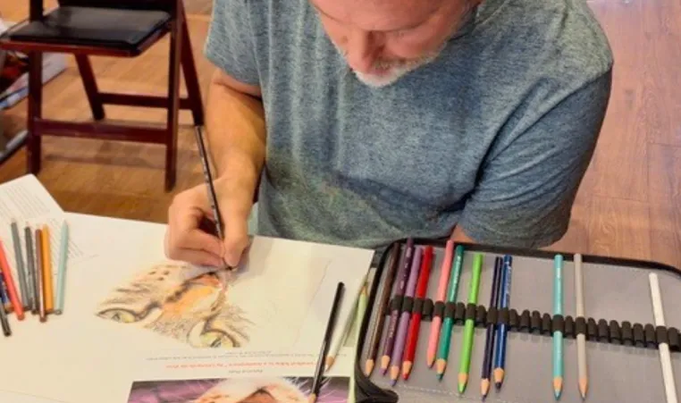 A man uses color pencils during a group art class.