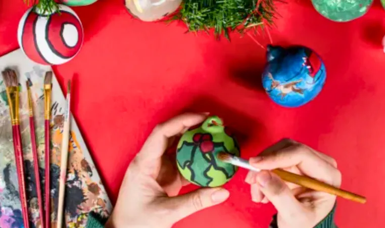A person paints a holiday-themed ornament.