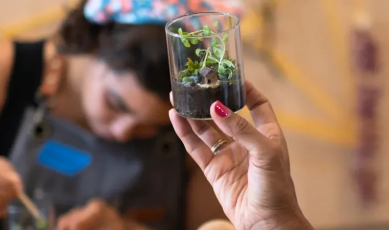 A person holds up a mini terrarium craft.
