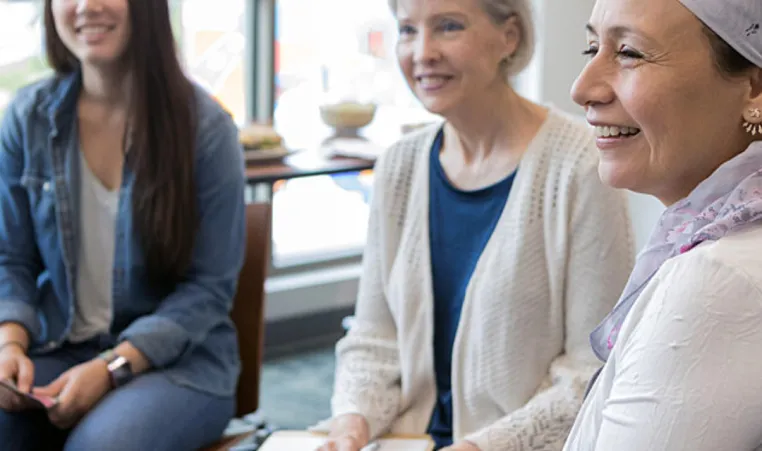 A group of diverse women sit together in a cancer support group for women.