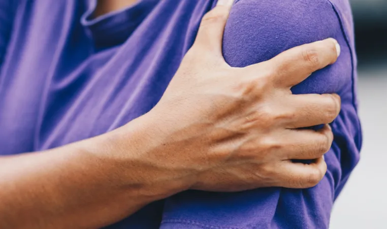 A close-up of a person holding their shoulder.