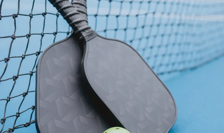 Two pickleball paddles on an outdoor court