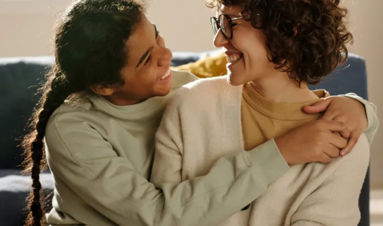 Mother smiling and embracing teenage daughter