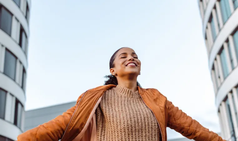A woman stands outside and smiles with confidence.