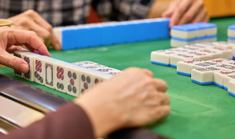 Close-up of two people playing mahjong.