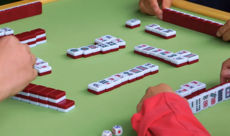 Close-up of three people's hands playing mahjong.