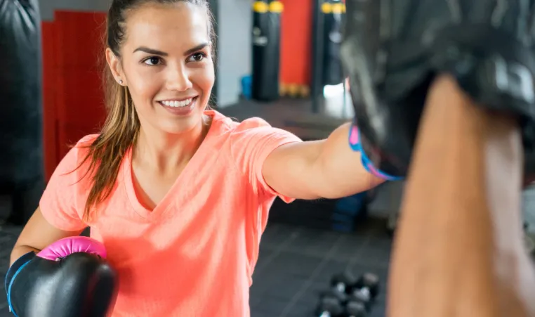 Woman smiling and practicing boxing with coach