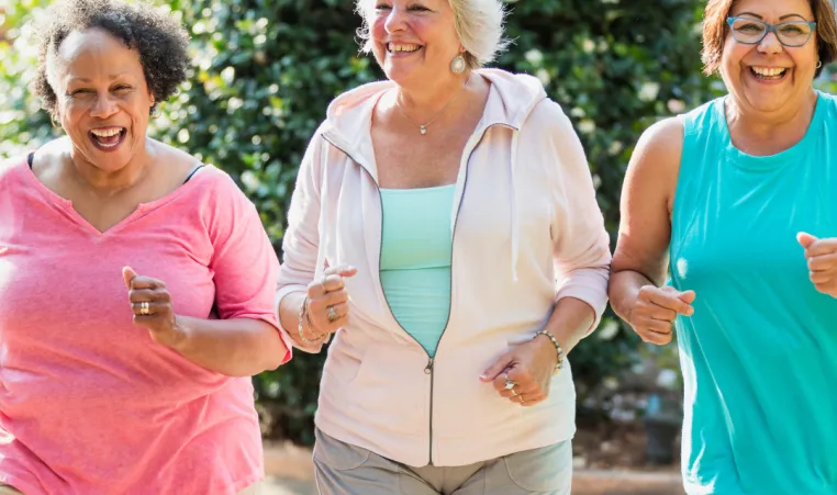 Three older women walk and talk in the park